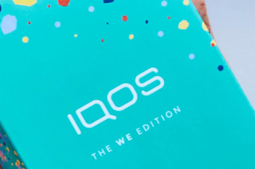 Zbliżenie logo IQOS znajdującego się na obwolucie pudełka nowego urządzenia WE Edition IQOS 3 DUO.​  ​