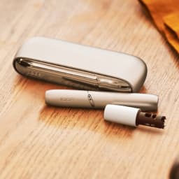 IQOS Originals Duo holder and pocket charger in Brilliant Gold color on a table