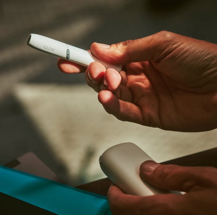 Mężczyzna trzyma w dłoni IQOS-a 3 DUO