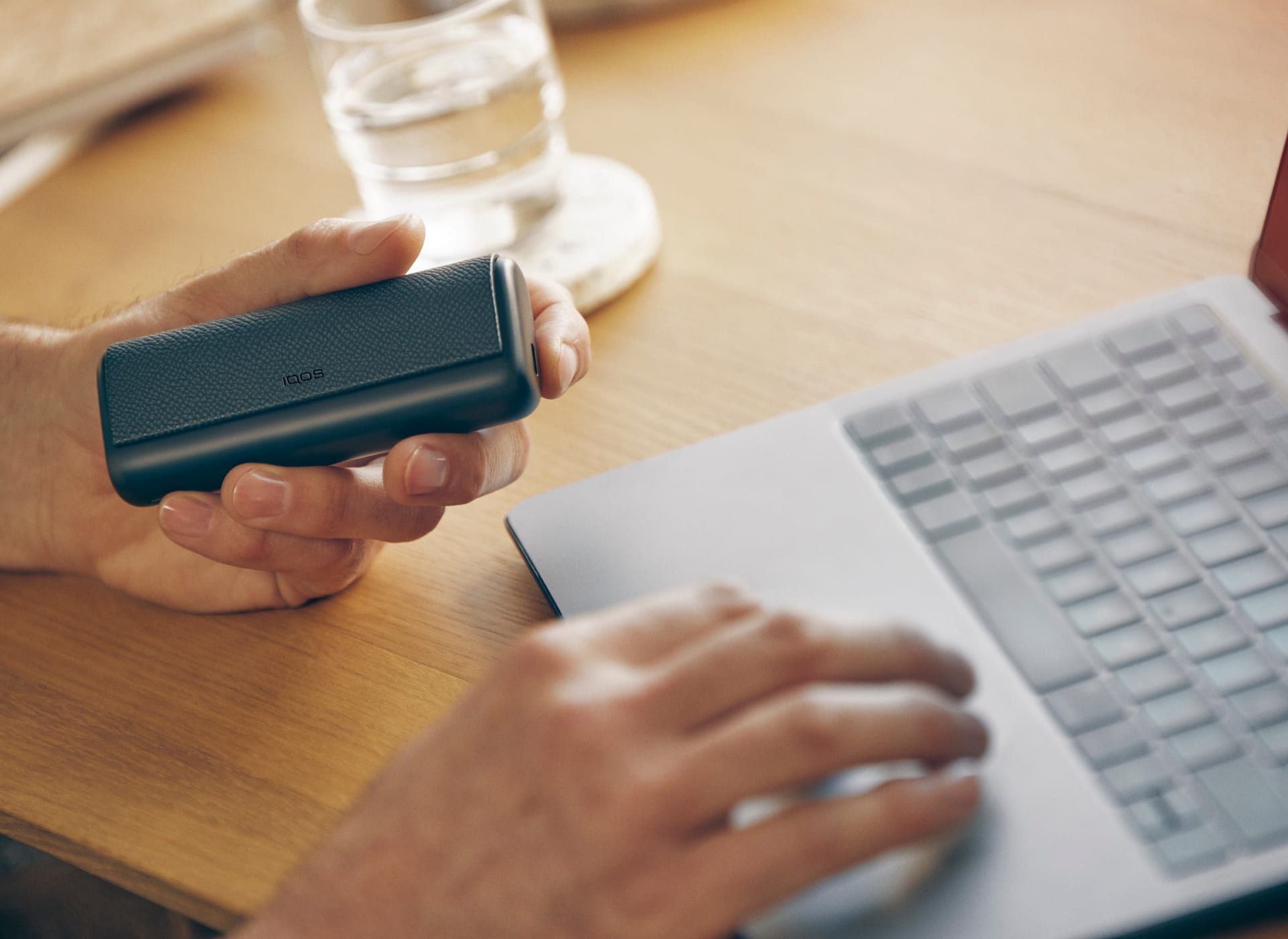 IQOS ILUMA PRIME w dłoni osoby korzystającej z laptopa