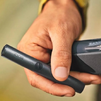 Mężczyzna trzyma w dłoni podgrewacz tytoniu IQOS ILUMA Prime w kolorze Obsidian Black
