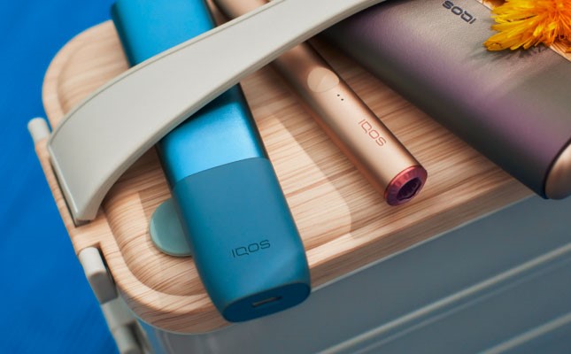 Trzy różne podgrzewacze z serii IQOS ILUMA leżące obok siebie