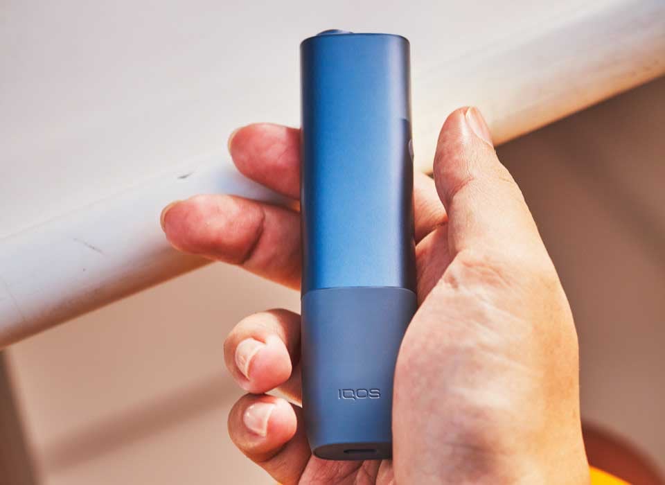Podgrzewacz IQOS ILUMA ONE w niebieskim odcieniu trzymany w dłoni