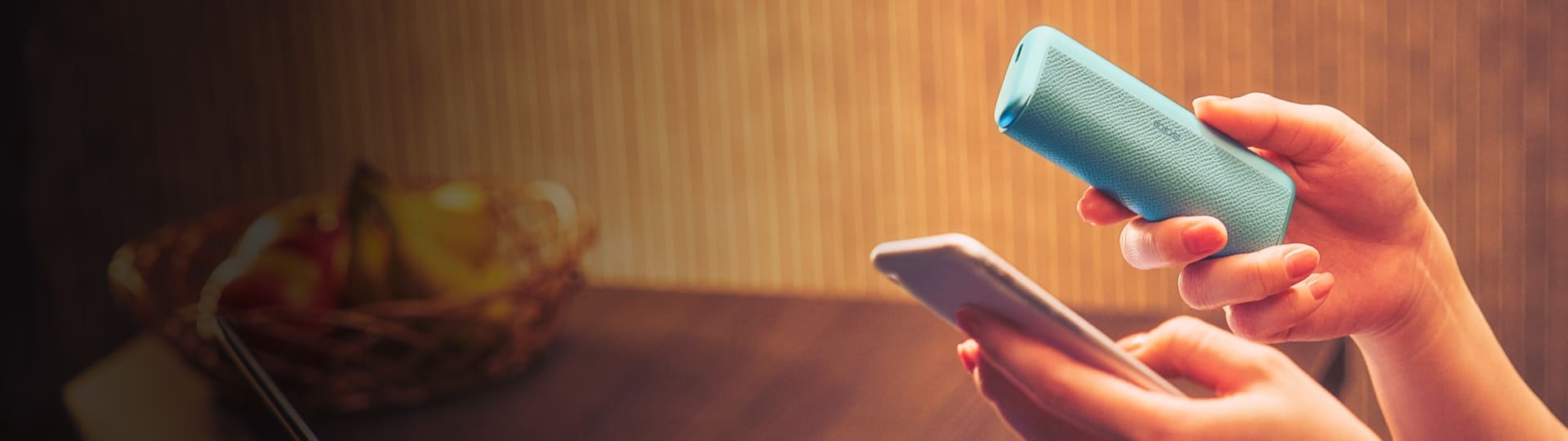 Ręce trzymające IQOS-a ILUMA i PRIME oraz telefon