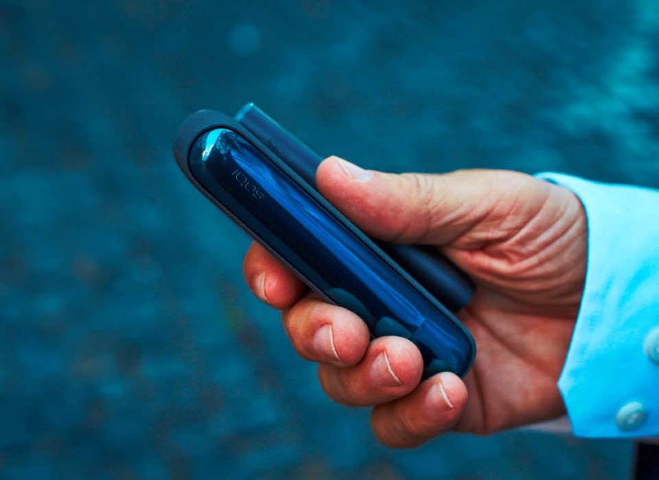 Podgrzewacz IQOS ILUMA w dłoni osoby przebywającej na dworze