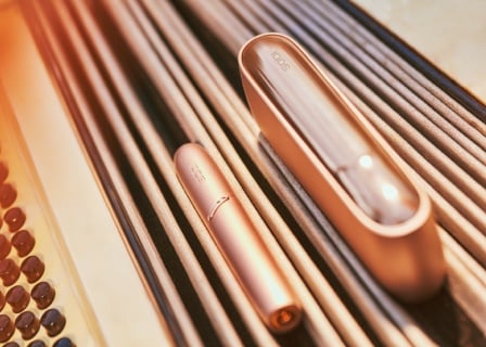 Brilliant gold IQOS 3 DUO holder and charger on an accordion's bellows