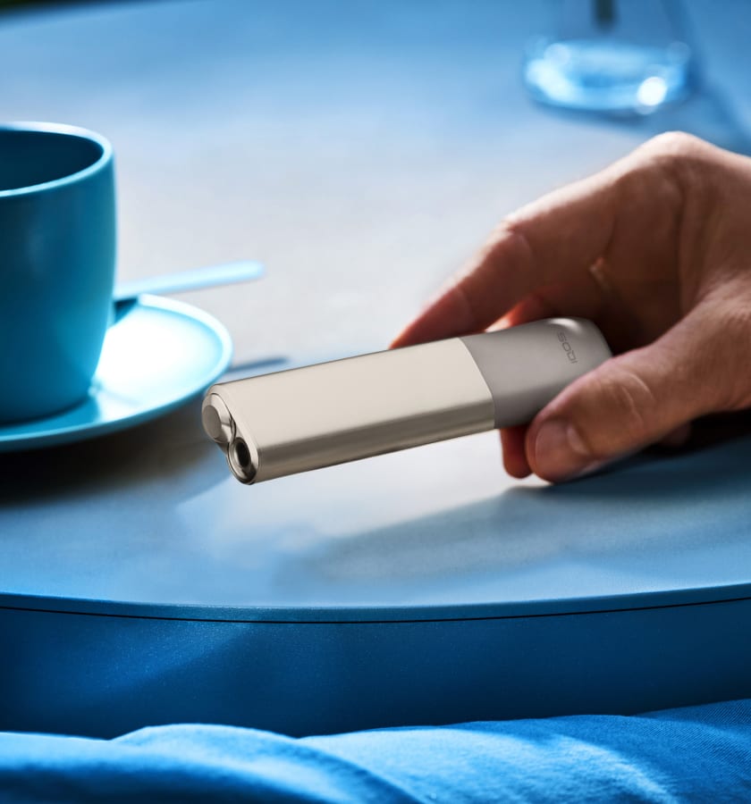 IQOS ILUMA ONE w kolorze Pebble Beige trzymany w dłoni