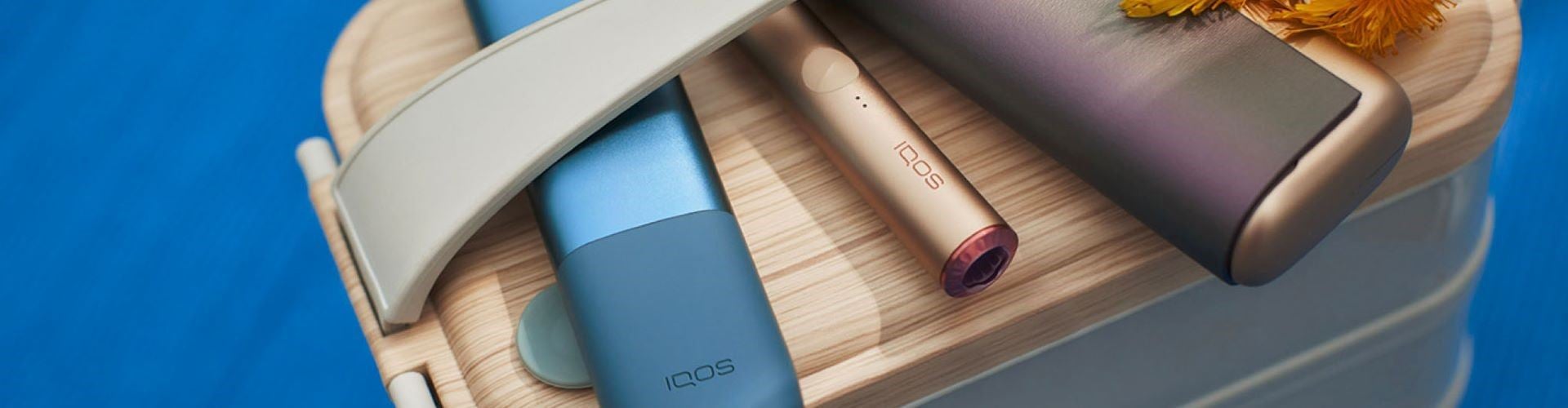 Trzy różne podgrzewacze z serii IQOS ILUMA leżące obok siebie