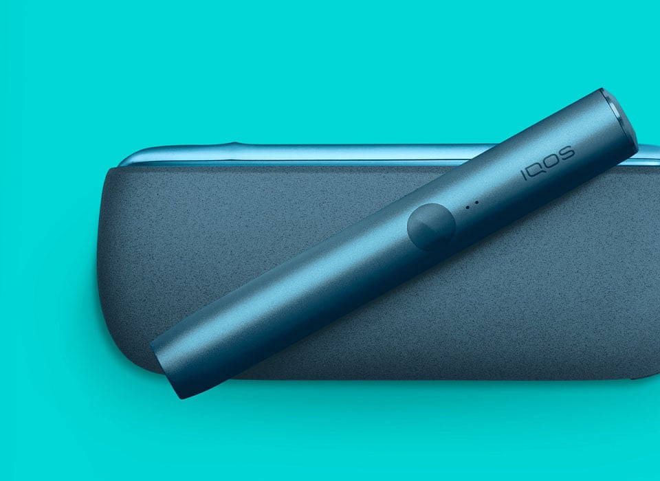 Podgrzewacz tytoniu IQOS ILUMA w niebieskim odcieniu na turkusowym tle