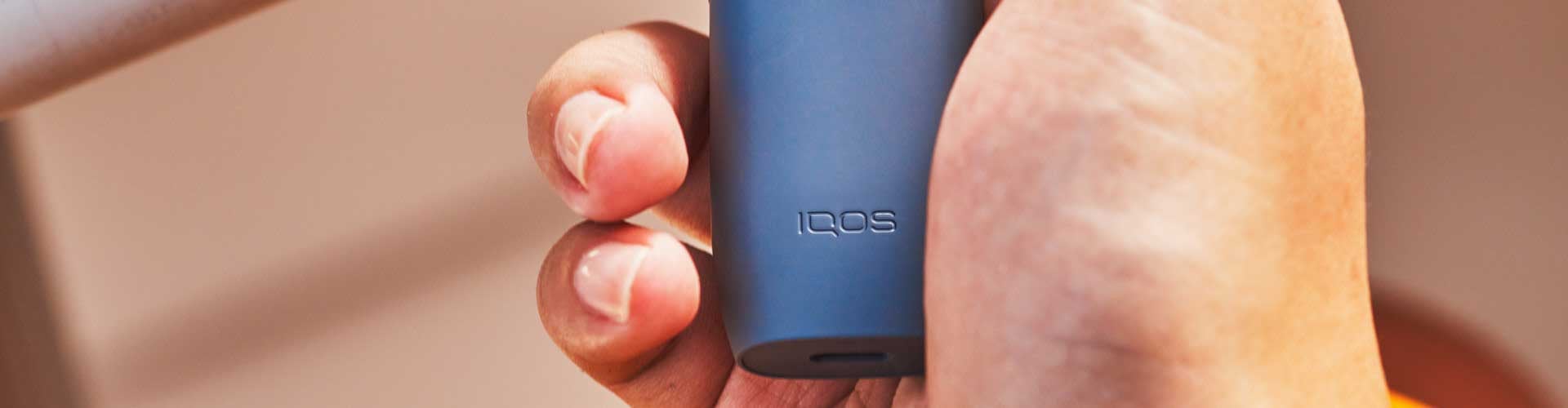 Podgrzewacz IQOS ILUMA ONE w niebieskim odcieniu trzymany w dłoni