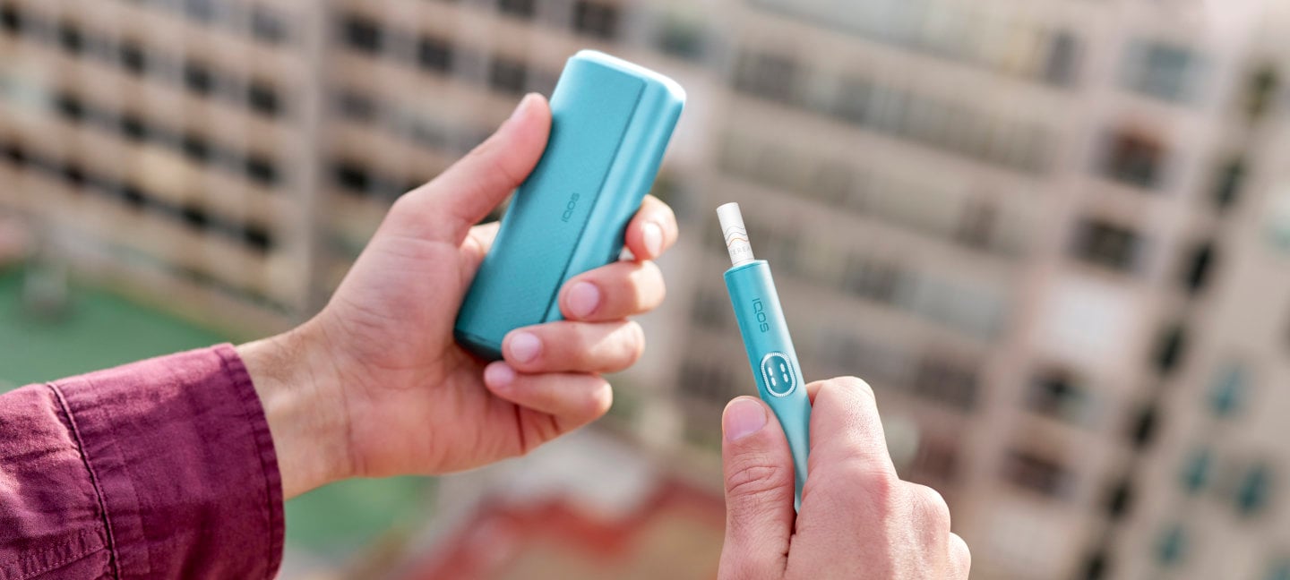 Podgrzewacz IQOS ILUMA i PRIME, niebieski, z włożonym wkładem tytoniowym, trzymane w dłoniach