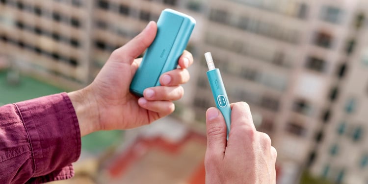 Podgrzewacz IQOS ILUMA i PRIME, niebieski, z włożonym wkładem tytoniowym, trzymane w dłoniach