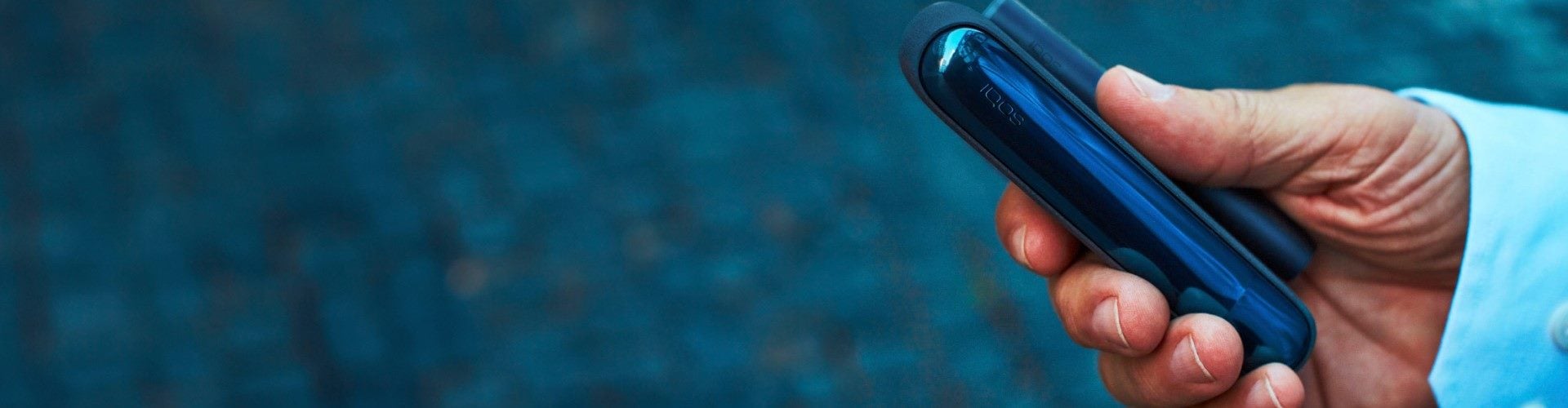 Podgrzewacz IQOS ILUMA w dłoni osoby przebywającej na dworze