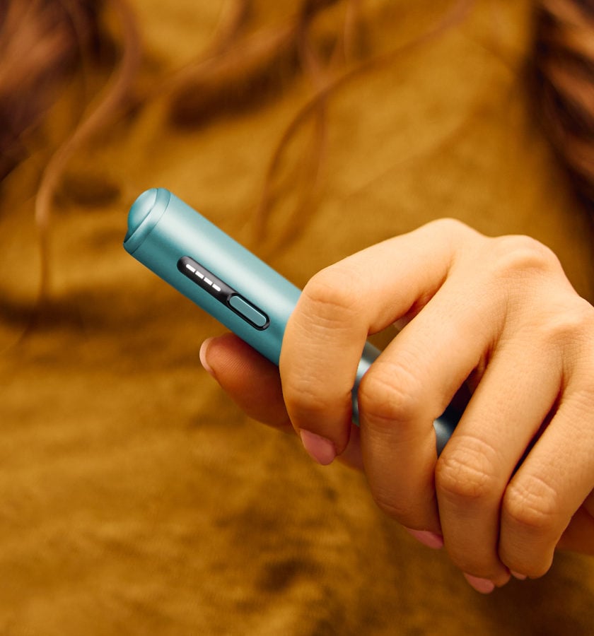 Podgrzewacz tytoniu IQOS ILUMA i ONE w kolorze Breeze Blue, trzymany w dłoni