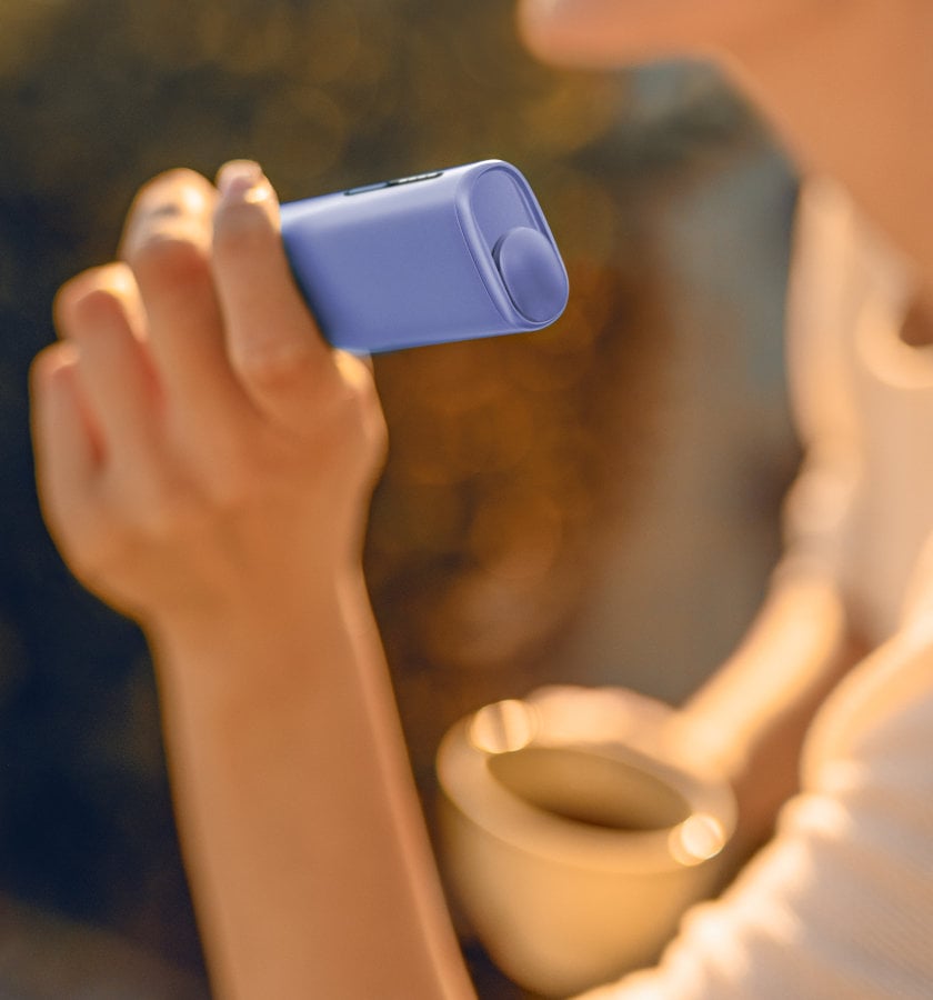 Podgrzewacz tytoniu IQOS ILUMA i ONE w kolorze Digital Violet trzymany w dłoni