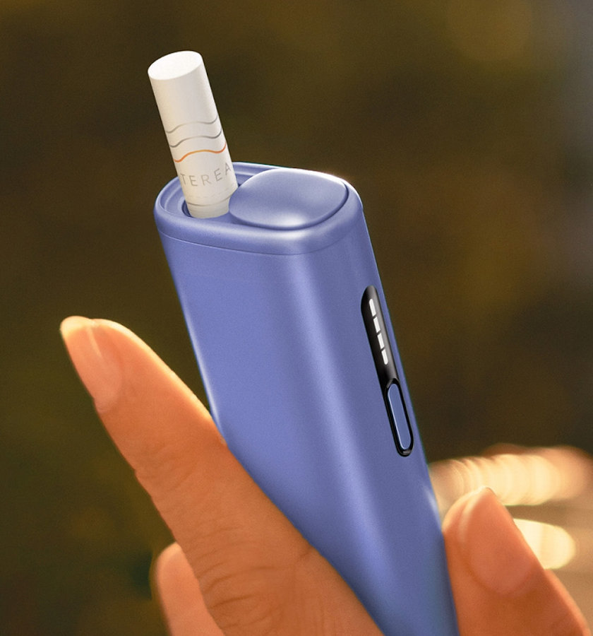 Zbliżenie na podgrzewacz IQOS ILUMA i ONE Digital Violet z wsuniętym wkładem tytoniowym TEREA