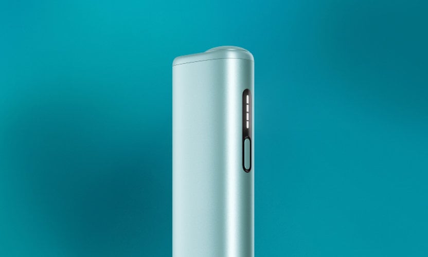 Podgrzewacz tytoniu IQOS ILUMA i ONE w kolorze Breeze Blue, stojący na turukusowym tle