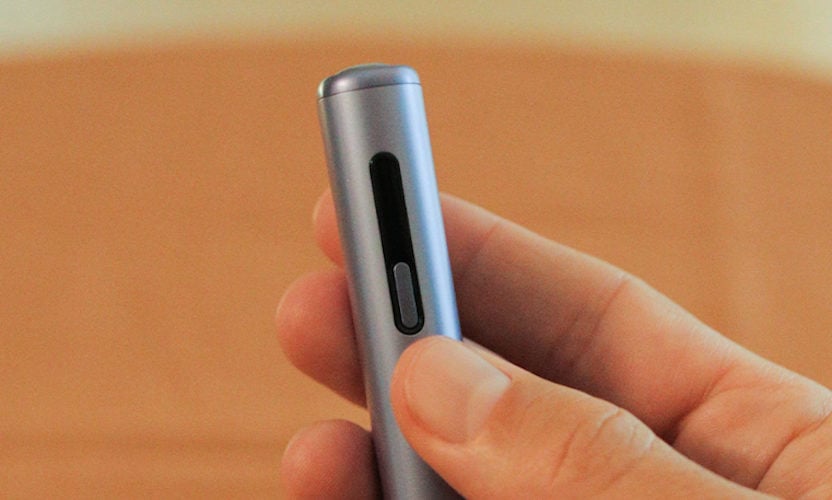 Podgrzewacz IQOS ILUM i ONE w dłoni, naciskającej jedej z przycisków na jego bocznej krawędzi