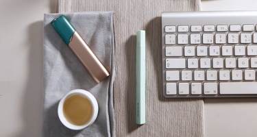 Green and coppery IQOS 3 MULTI kit on a working desk