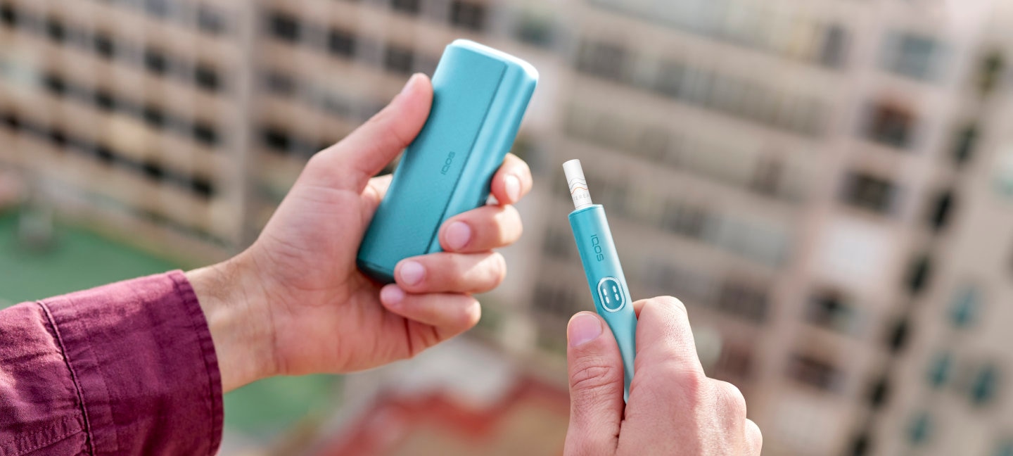 Podgrzewacz IQOS ILUMA i PRIME, niebieski, z włożonym wkładem tytoniowym, trzymane w dłoniach