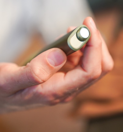 Zamknięty IQOS ILUMA ONE w kolorze zielonym w dłoni, widoczny z góry