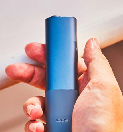 Niebieski IQOS ILUMA ONE w dłoni w ujęciu z góry