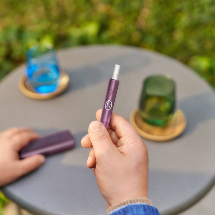 Podgrzewacz IQOS ILUMA i PRIME z wsuniętym wkładem, trzymany w dłoni