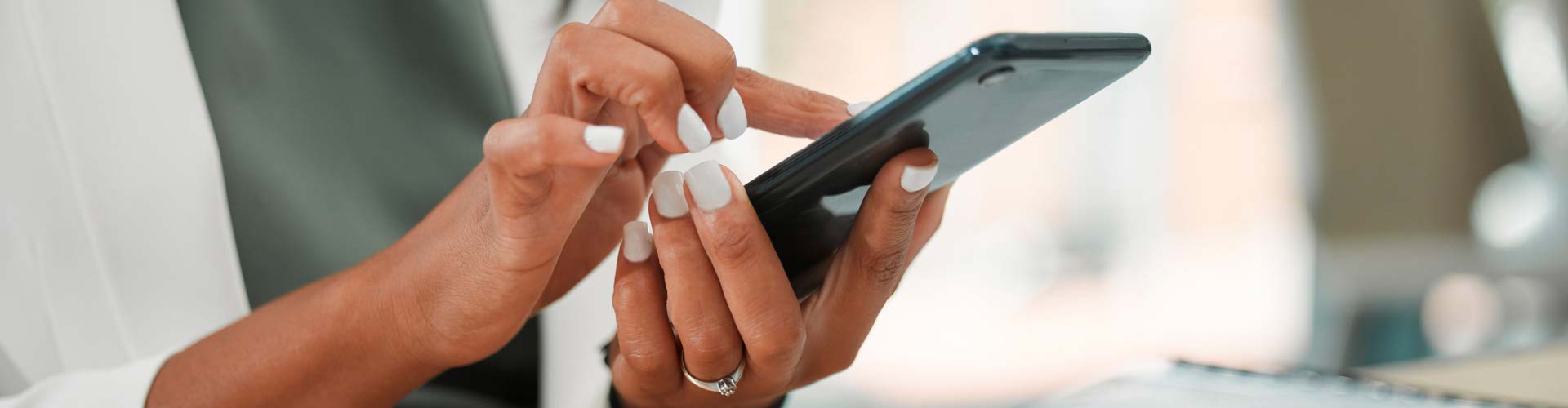 Kobieta siedząca z laptopem przy biurku, korzysta z telefonu 