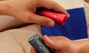 Dwa podgrzewacze BONDS by IQOS, czerwony oraz czarny, trzymane w dłoniach