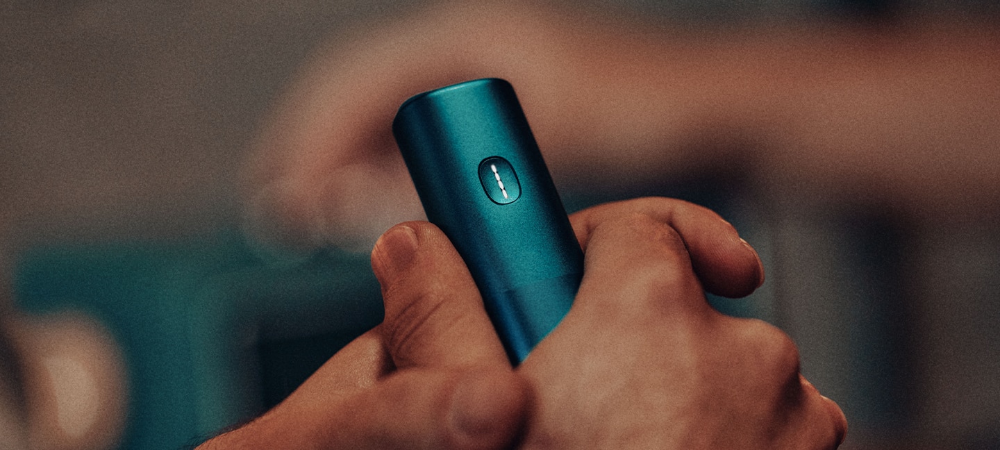 Podgrzewacz tytoniu BONDS by IQOS w kolorze niebieskim trzymany w dłoniach