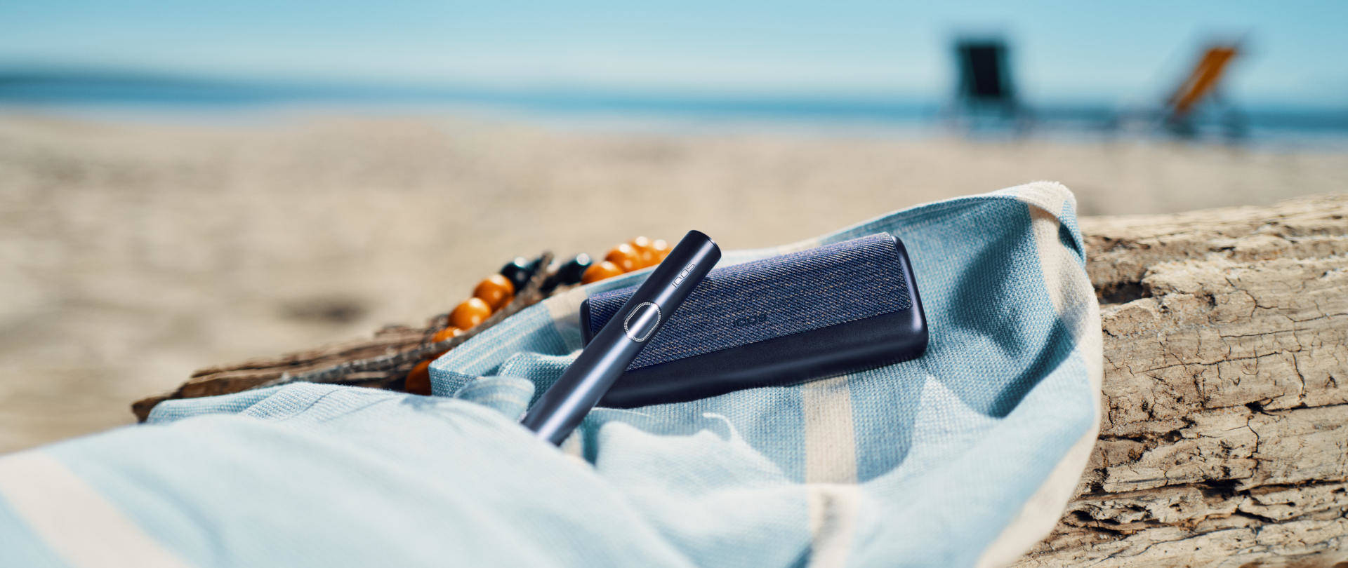 Podgrzewacz tytoniu IQOS ILUMA i PRIME w kolorze czarnym na plaży 
