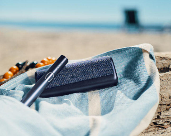 Podgrzewacz tytoniu IQOS ILUMA i PRIME w kolorze czarnym na plaży 
