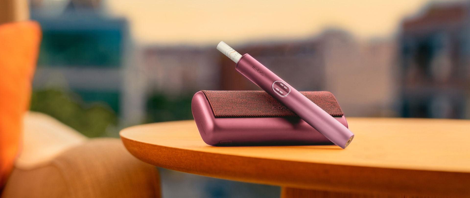 IQOS ILUMA i PRIME w kolorze bordowym na stole 