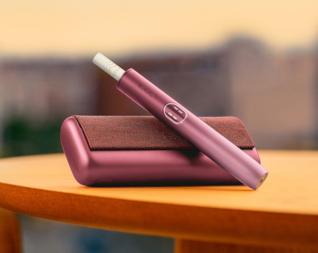 IQOS ILUMA i PRIME w kolorze bordowym na stole 