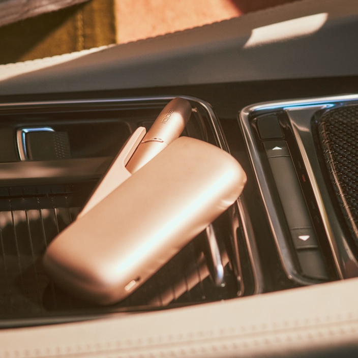 Brilliant gold IQOS device in car's centre panel