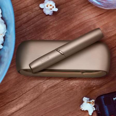 An IQOS device next to a bowl of popcorn.