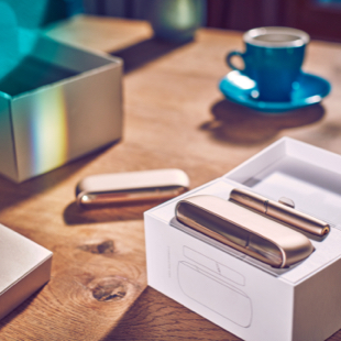 IQOS 3 DUO in its packaging and a cup of coffee on the table