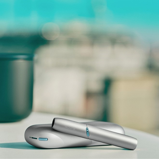 Silver IQOS ORIGINALS DUO on a coffee table.