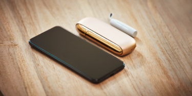 A mobile and a gold IQOS kit on a table