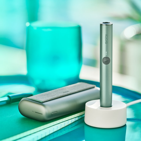 A Jade Green IQOS ILUMA PRIME Holder in a charging station
