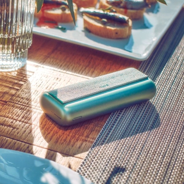 A Jade Green IQOS ILUMA PRIME Pocket Charger on a table