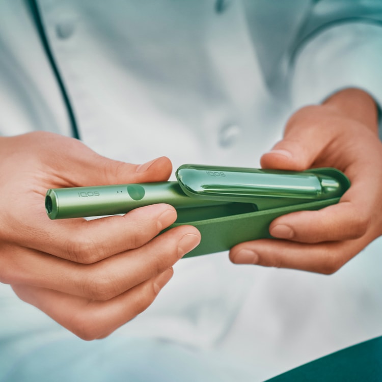 Close up of a chef's hands  opening a jade green IQOS ILUMA device.